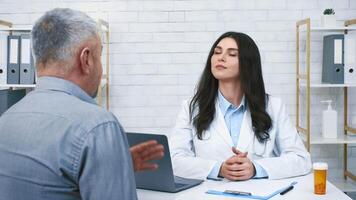 A healthcare professional is discussing health issues with a senior man patient in a well-lit, contemporary clinic environment. Both appear engaged in the conversation. video