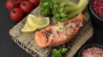 Grilled salmon with salt and spices, broccoli, tomatoes, rice on a dark concrete background video