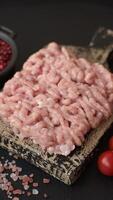 Raw minced chicken with salt, spices and herbs on a dark concrete background video