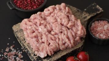Raw minced chicken with salt, spices and herbs on a dark concrete background video