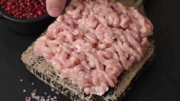 Raw minced chicken with salt, spices and herbs on a dark concrete background video