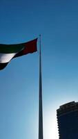 Low angle view of a waving flag against blue sky. Action. Dubai, UAE, architecture and waving flag. video