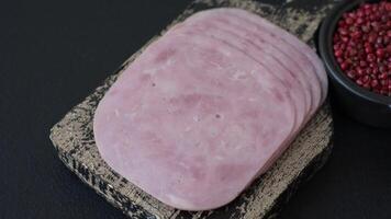 Ham, spam with salt, spices and herbs cut into slices on a dark concrete background video