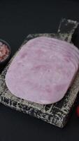 Ham, spam with salt, spices and herbs cut into slices on a dark concrete background video