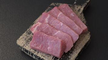Juicy beef cut into slices with salt, spices and herbs on a dark concrete background video