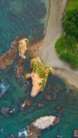 Top view of coast with rocks in water and forest. Clip. Amazing nature of coast with beautiful rocks and clear water. Wild coast with rocks in turquoise water and green forest on sunny day video