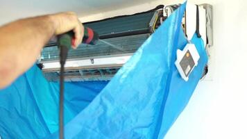 Cleaning air conditioning unit in a blue tarp setup during the summer afternoon video
