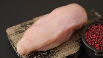 Pieces of raw chicken or turkey fillet with salt, spices and herbs on a dark concrete background video