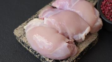 Fresh raw chicken thigh fillets with salt, spices and herbs on a dark concrete background video
