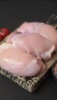 Fresh raw chicken thigh fillets with salt, spices and herbs on a dark concrete background video
