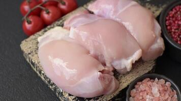 Fresh raw chicken thigh fillets with salt, spices and herbs on a dark concrete background video