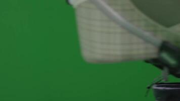 A person in a purple jacket stands in front of a green screen video