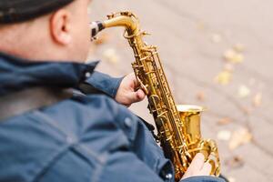 A saxophonist performs in a serene park during autumn while seated on a bench photo