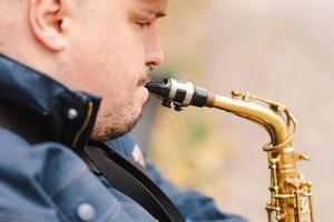 A saxophonist performs in a serene park during autumn while seated on a bench photo
