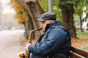 A saxophonist performs in a serene park during autumn while seated on a bench photo