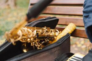 A saxophonist performs in a serene park during autumn while seated on a bench photo