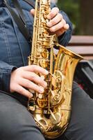 A saxophonist performs in a serene park during autumn while seated on a bench photo
