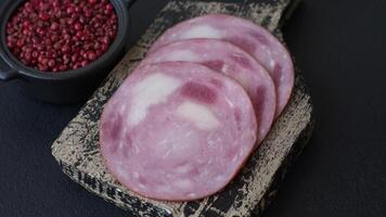Ham cut into slices with salt and spices on a dark concrete background video