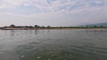 Exploring the tranquil river landscape with gentle waves and lush greenery along the shoreline in a serene afternoon against a clear sky video