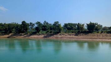 Exploring the serene riverside landscape in the afternoon sun with lush greenery and clear turquoise waters in a tranquil setting video