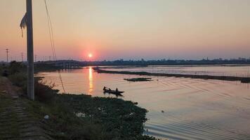 Sunset view on tranquil river with boaters enjoying a peaceful evening in a serene landscape video