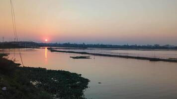 Beautiful sunset over the river with tranquil water reflections and distant urban skyline in the evening video