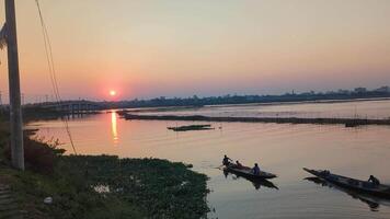Sunset view over river with fishermen in small boats during evening hours in a serene urban landscape video