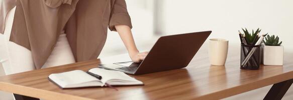 Office Person. Unrecognizable european girl standing at desk in modern office using laptop, copyspace, panorama photo