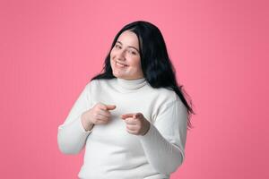 Gotcha. Positive Plus Size Model Pointing Fingers At Camera, Isolated On Pink Background, Free Space photo