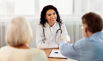 Assistance Concept. Mexican doctor and senior patient handshaking in the office, copyspace photo