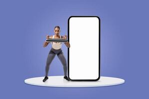 A woman performs strength training with a resistance band while positioned in front of a large blank screen. She appears focused and engaged in her workout routine. photo