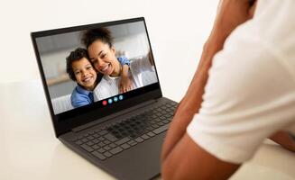 A child and a parent smile at each other during a call, showcasing their connection and happiness. The cozy background highlights their warm interaction, emphasizing love and togetherness. photo