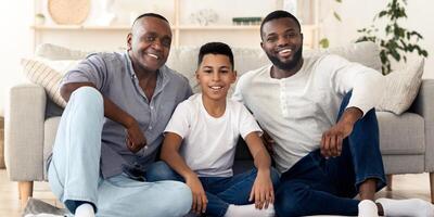 Three generation men family portrait. Happy little boy posing with his young father and senior grandfather at home, looking at camera, free space photo