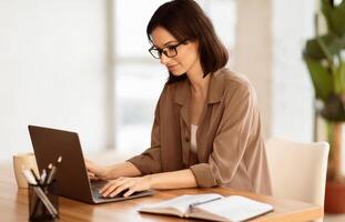 Making New Project. Portrait of satisfied girl in eyeglasses using laptop, working at home, writing blog, free space photo