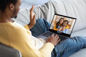 Two friends share a heartfelt moment during a call on a laptop while sitting on a comfy couch, conveying warmth and connection in a relaxed indoor setting. photo