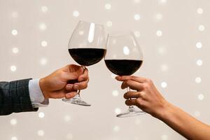 Toast for us. Romantic couple holding and clinking two glasses of red wine on date in restaurant, closeup, copy space photo