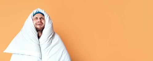 Doesnt want get up. Funny sad man wrapped in blanket on yellow background photo