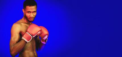 Shirtless Boxer In Boxing Gloves Standing In Ready-To-Fight Position Posing Looking At Camera On Blue Studio Background With Red Lights photo
