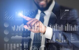 Modern technology. Businessman choosing with finger analytic diagram with data on transparent screen photo