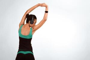 Fitness. African American Girl Stretching Arms Exercising Standing With Her Back To Camera On Yellow Studio Background. Free Space photo