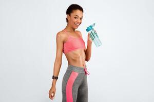 Fitness And Hydration. Slim African American Woman Holding Water Bottle Smiling At Camera On Pink Studio Background. Copy Space photo