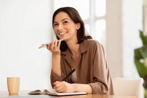 Technology And Communication Concept. Happy woman using voice command recorder on mobile phone and taking notes photo
