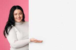 Place For Your Ad. Beautiful Plus Size Girl Holding And Pointing At Blank White Advertisement Board With Open Palm, Panorama photo