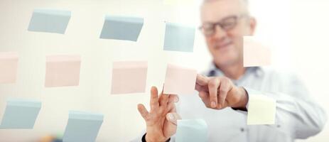 Presentation Concept. Successful middle-aged business man putting his ideas on sticky notes in conference room photo