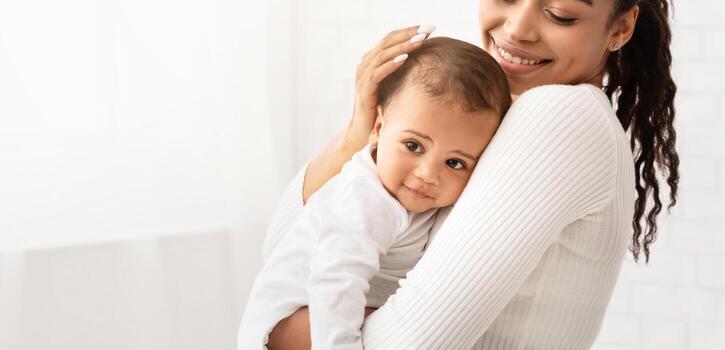 contento africano mamá participación bebé niñito abrazando linda pequeño hija posando en pie adentro. maternidad dejar, maternidad y felicidad, alegría de niño cuidado. de la madre amor concepto. recortado foto