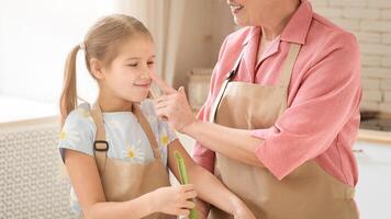 Fun baking time. Smiling older lady touching her granddaughter's nose in kitchen, empty space photo