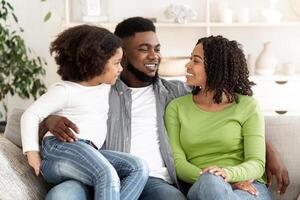 Portrait of happy black family resting together on couch at home, cuddling and smiling, enjoying time together, free space photo