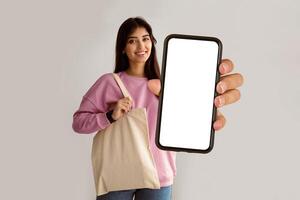 Zero Waste. Millennial Woman Showing Blank Eco Bag And Gesturing Thumbs Up Posing Standing On White Studio Background, Smiling To Camera. I Like Ecology Friendly Lifestyle, No More Plastic Concept photo