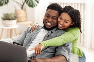 Online Shopping Concept. Black Married Couple Using Laptop At Home, Ordering Something In Internet Together photo