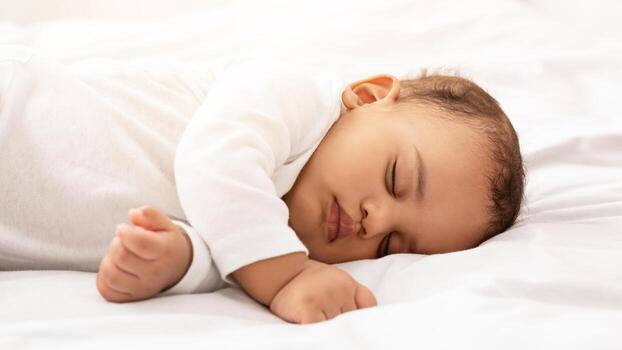 linda africano bebé niñito dormido en lado pacíficamente acostado con ojos cerrado en cama a hogar. de cerca de pequeño infantil niño descansando durante tiempo de día dormir concepto. foto